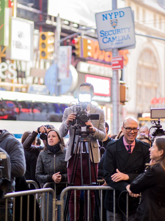 Journalists and photographers capturing live events in Times Square, New York City.