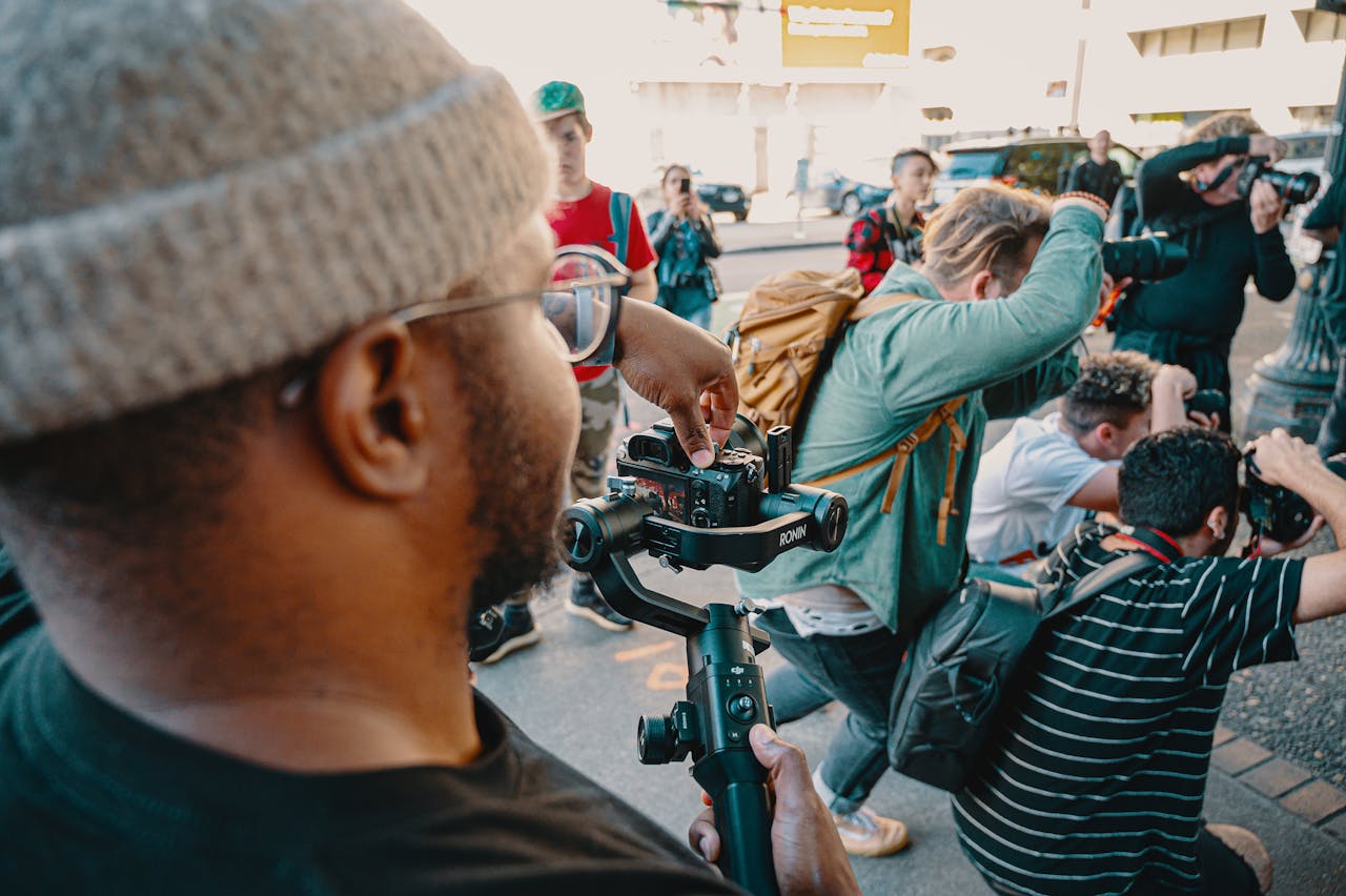 Photographers gather on a city street capturing dynamic shots during the day.